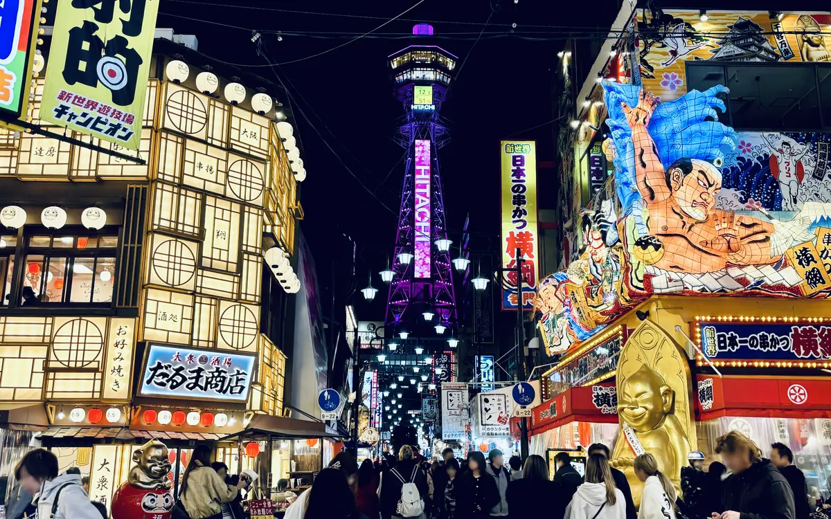 Tsutenkaku Tower lit up at night above the neon signs of Shinsekai, Osaka